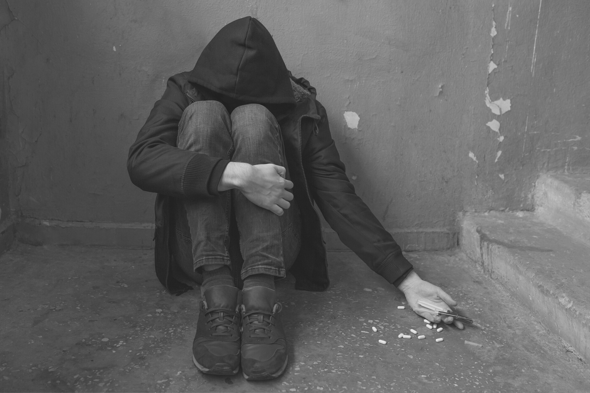 A male drug addict experiencing a drug addiction crisis after prolonged use of drugs and alcohol. Addiction and drug abuse concept.